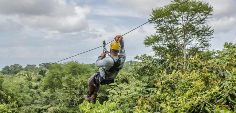 Person ziplining over a lush tropical forest