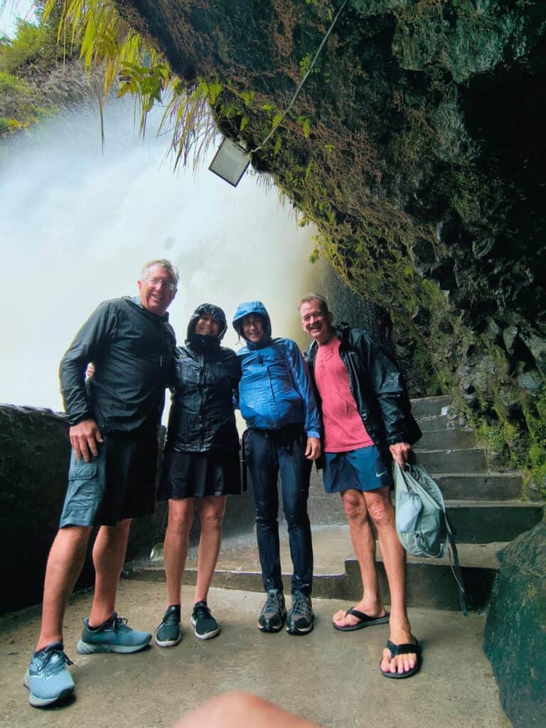 Four friends in rain jackets by waterfall
