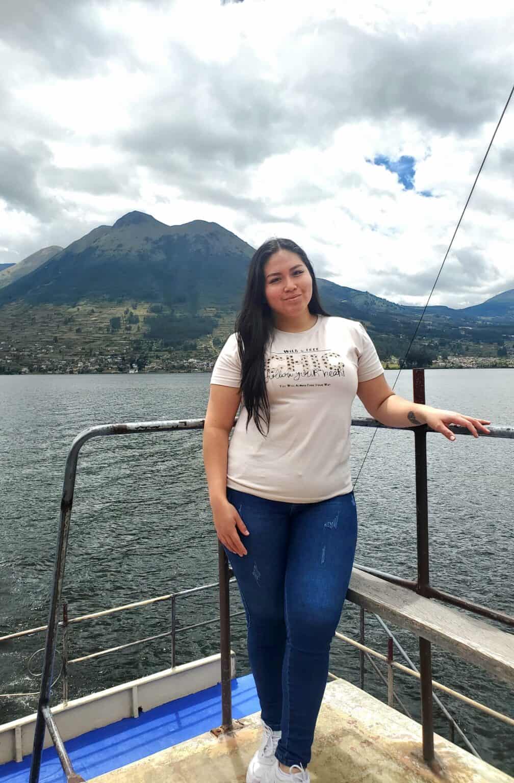 Woman standing on boat with mountain lake backdrop