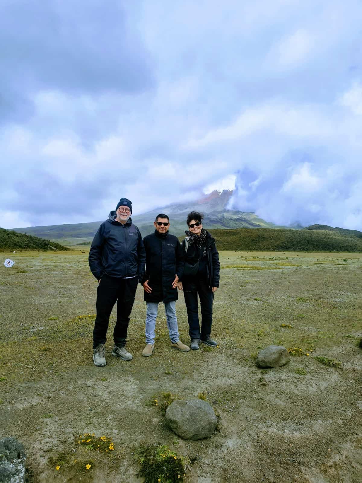 Three people posing before cloudy mountain landscape