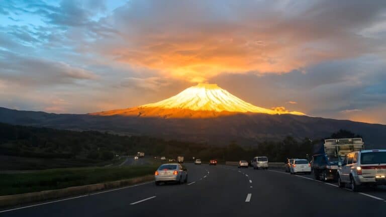 Highway leading toward glowing mountain at sunset