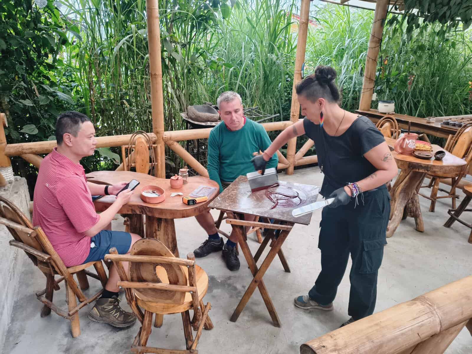 Woman demonstrating chocolate making to two seated men
