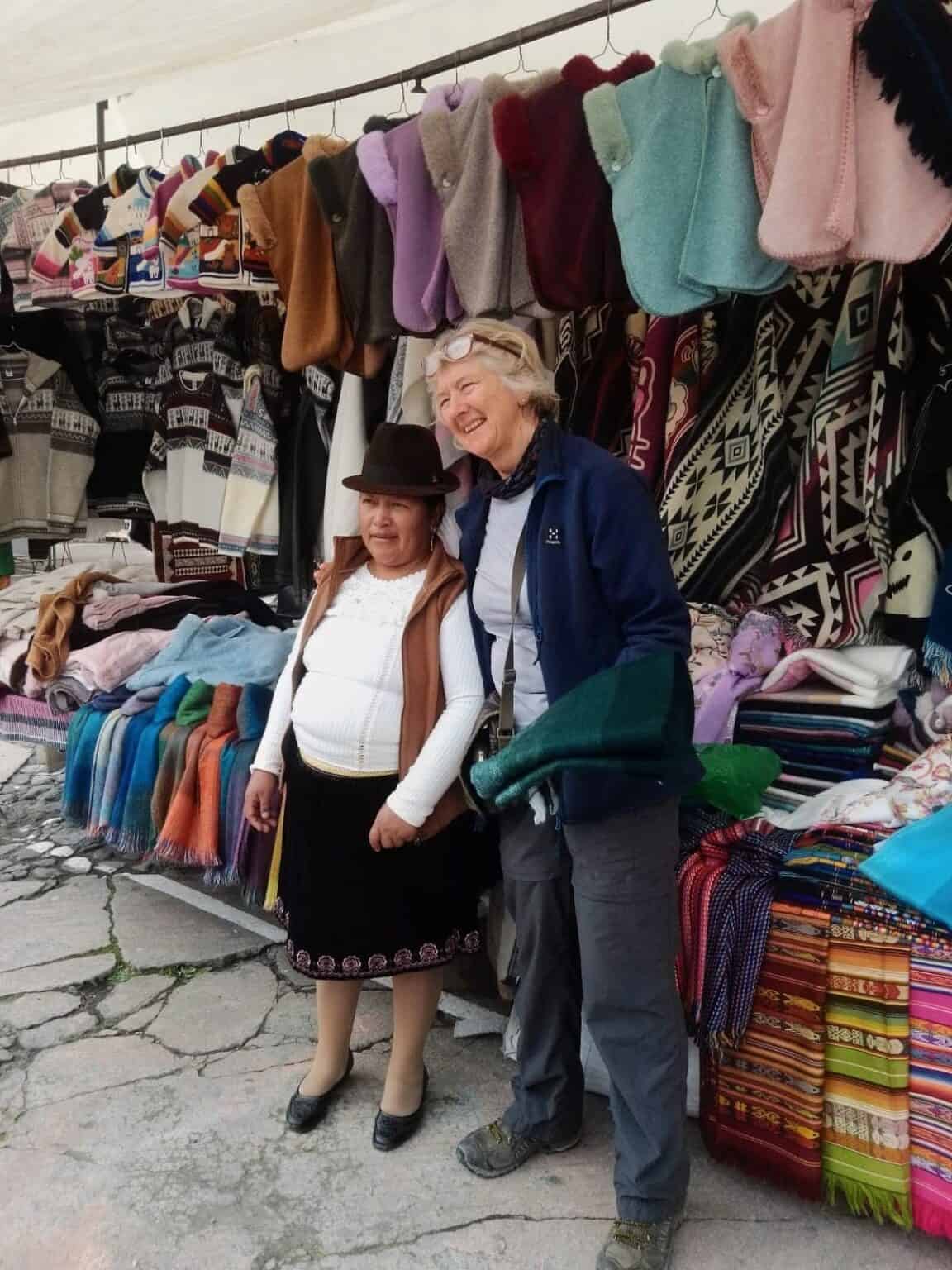 Two women at colorful outdoor textile market stall