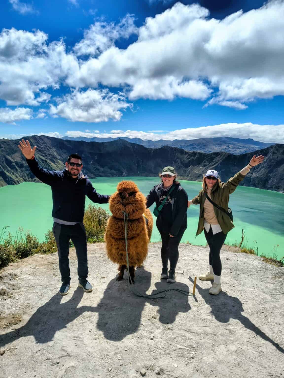Three travelers with alpaca by turquoise crater lake