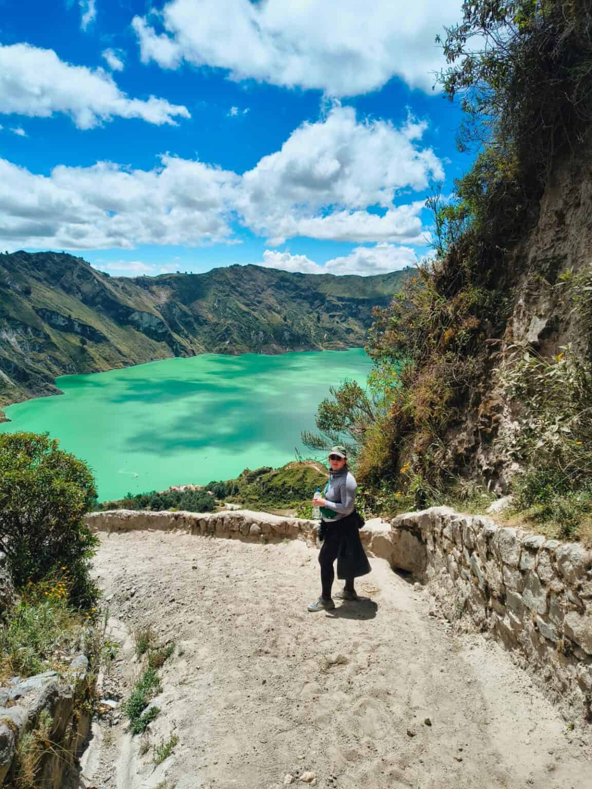 Hiker overlooking turquoise crater lake and mountains