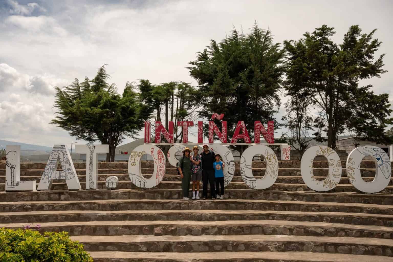 Family posing at Intiñan Equator monument sign