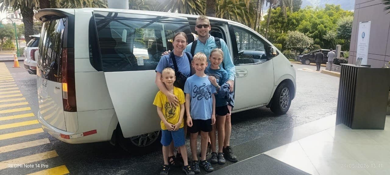 Family standing beside white van outdoors