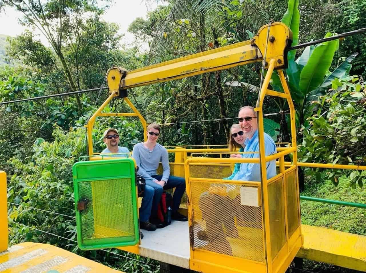 People riding yellow cable car in lush forest