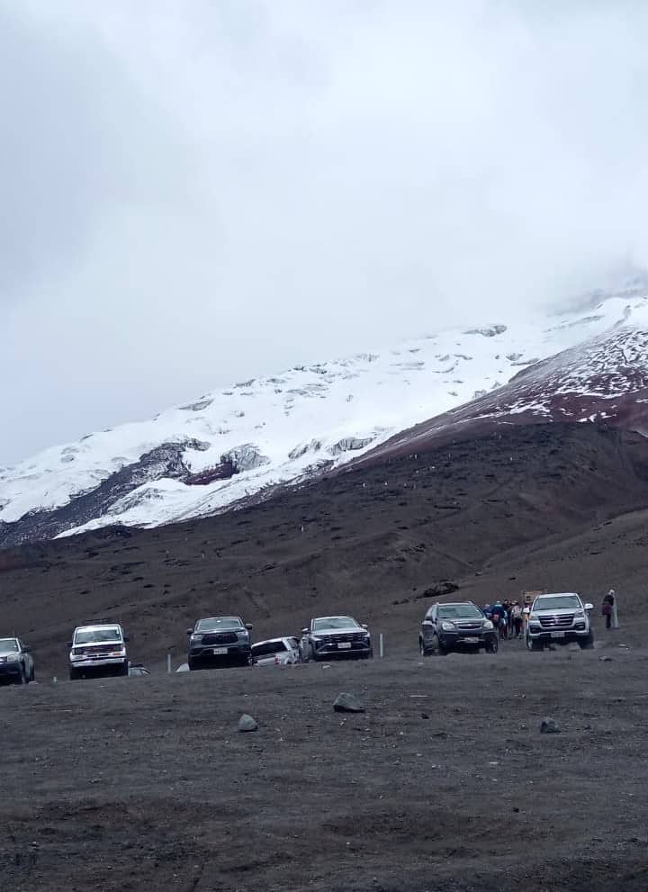 Parked SUVs below snow-covered mountain landscape