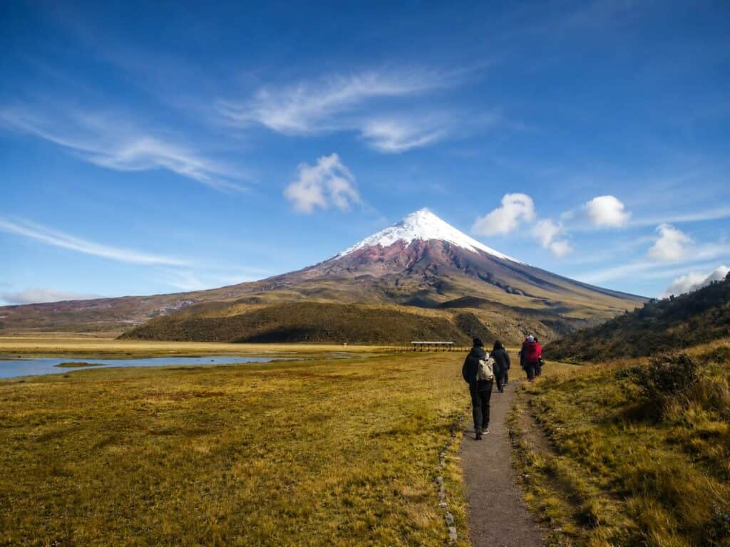 Hikers walking toward snow-capped mountain volcano