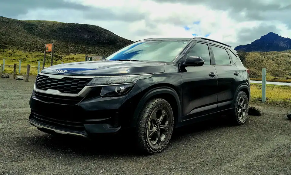 SUV negro aparcado en paisaje montañoso nublado