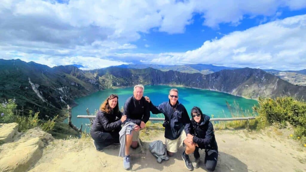 Four hikers at turquoise crater lake viewpoint