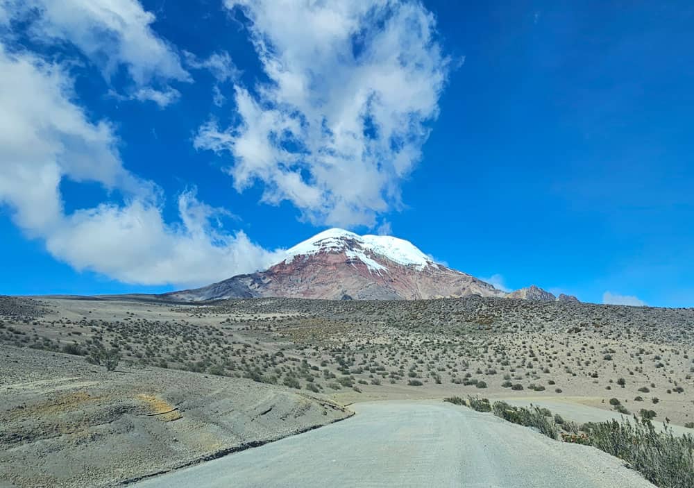Snow-capped mountain above arid road and shrubland