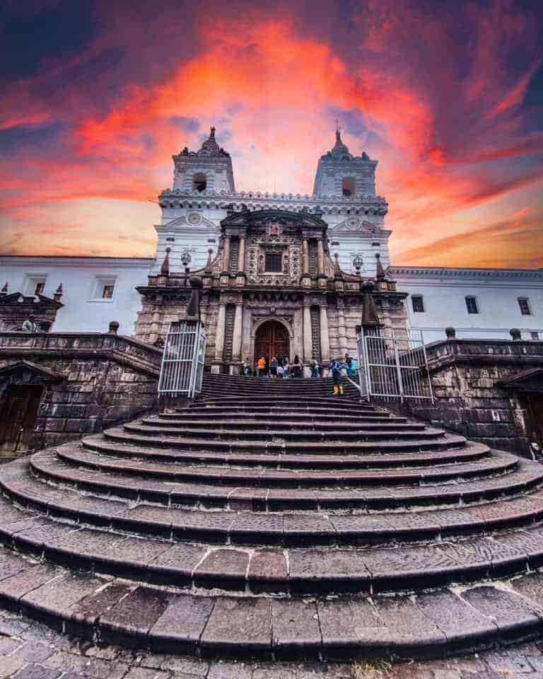 Historic cathedral entrance beneath a vivid red sunset sky