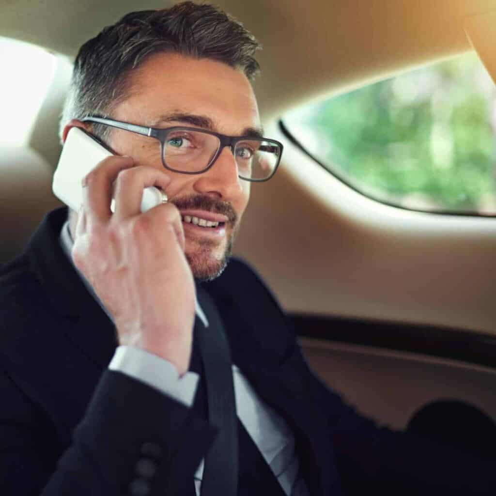 Businessman talking on smartphone in the back seat of car